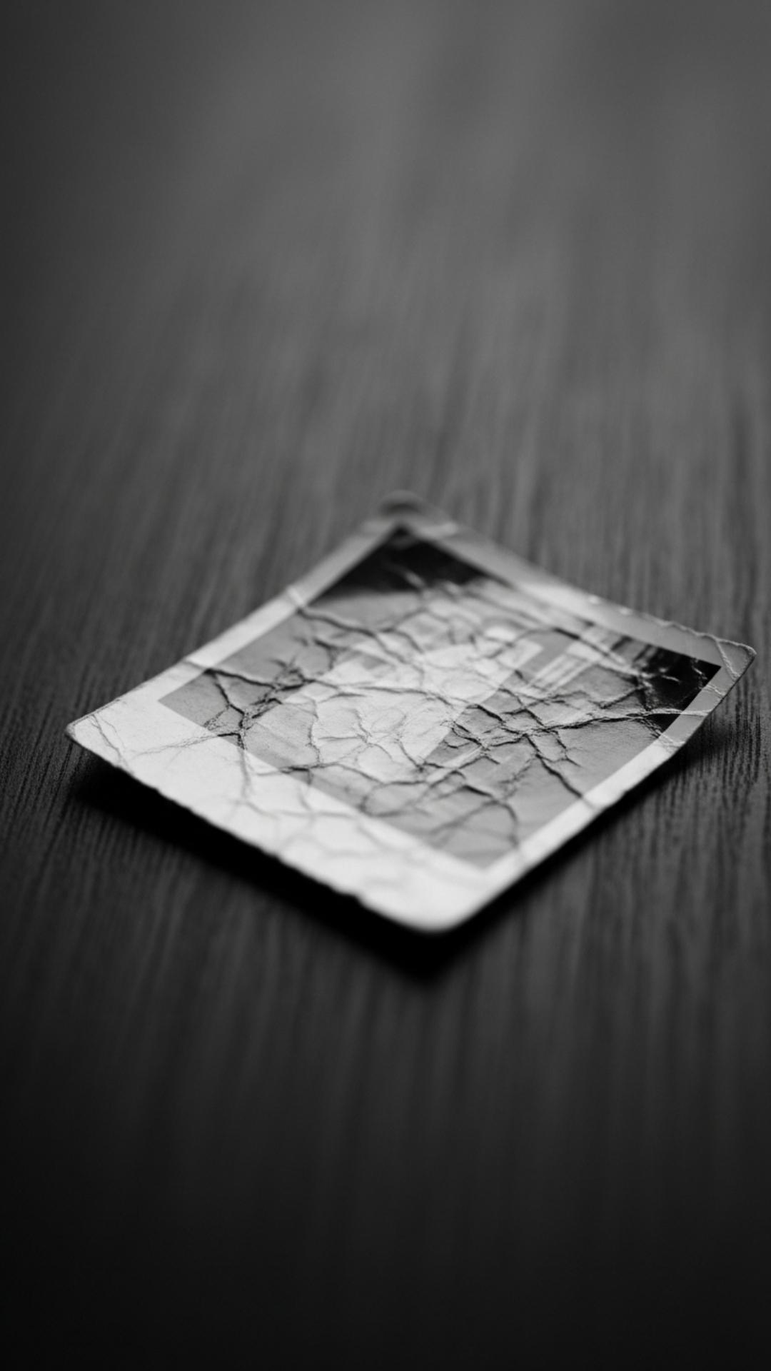A single old, faded photograph on a dark surface, symbolizing bittersweet memories, past regrets, and nostalgic sadness.