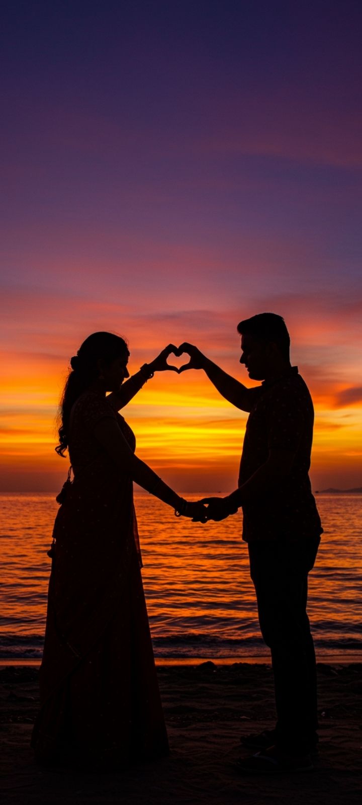 Love DP of a couple forming a heart with hands against a sunset silhouette.
