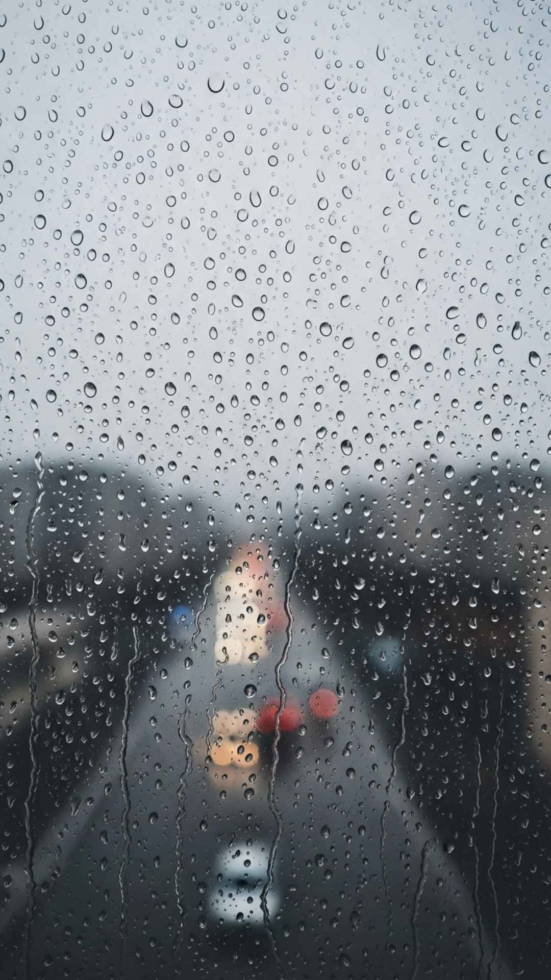 Close-up of rain droplets on a window, with a blurred, melancholic background, symbolizing a sad and reflective mood.