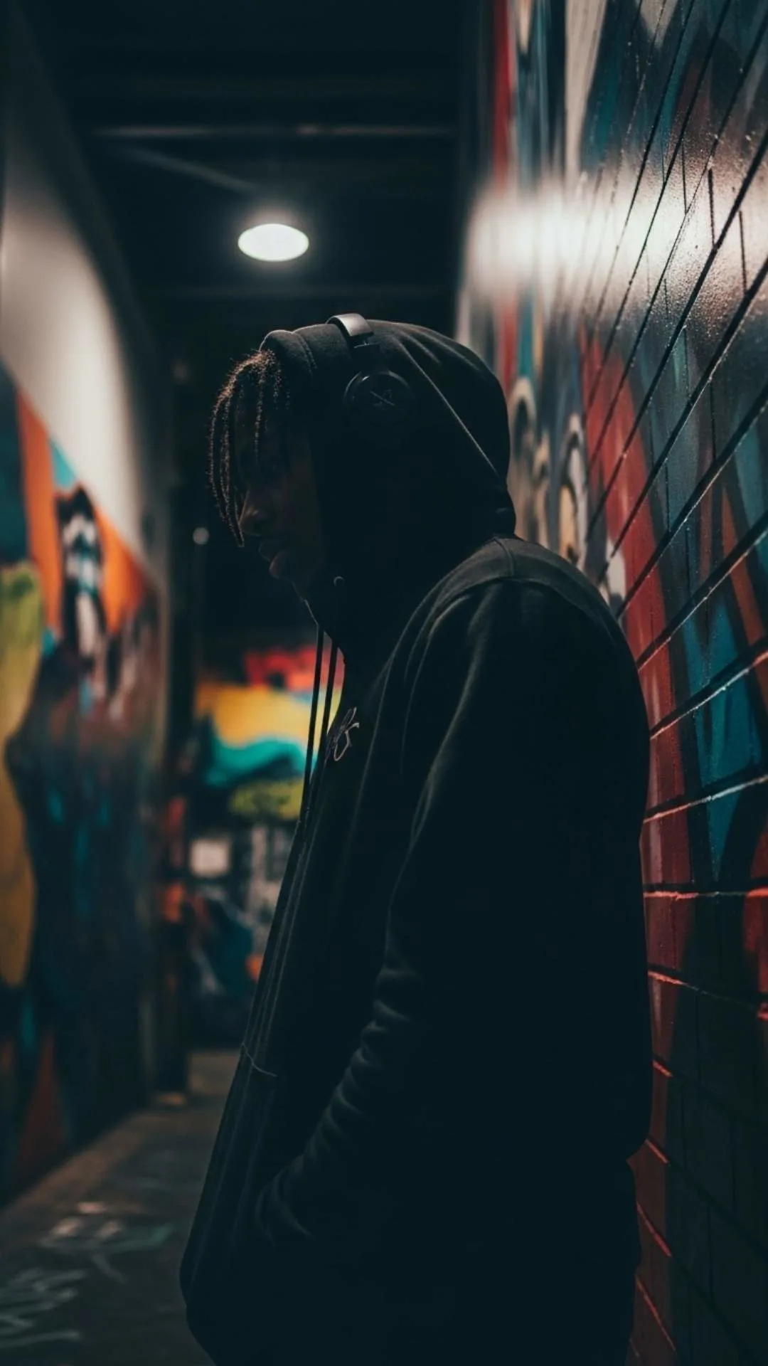 Hooded figure against vibrant street art in an alley, a raw urban Instagram DP inspired by Indian hip-hop culture.