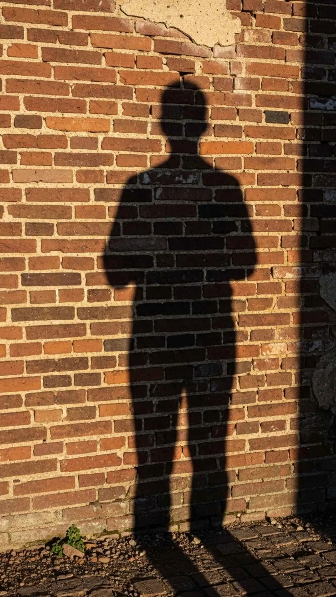 Long shadow on brick wall, conveying quiet contemplation