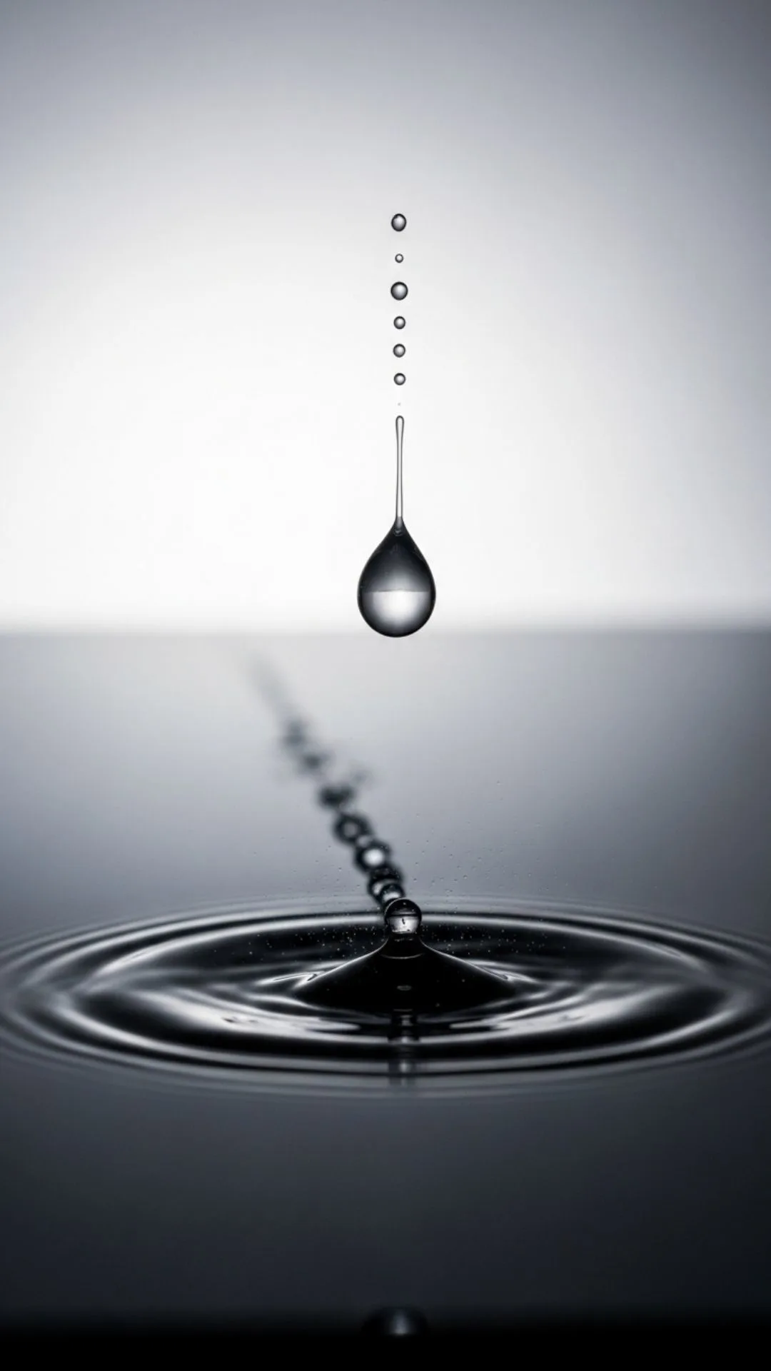 Teardrop falling on reflective surface, conveying gentle emotion